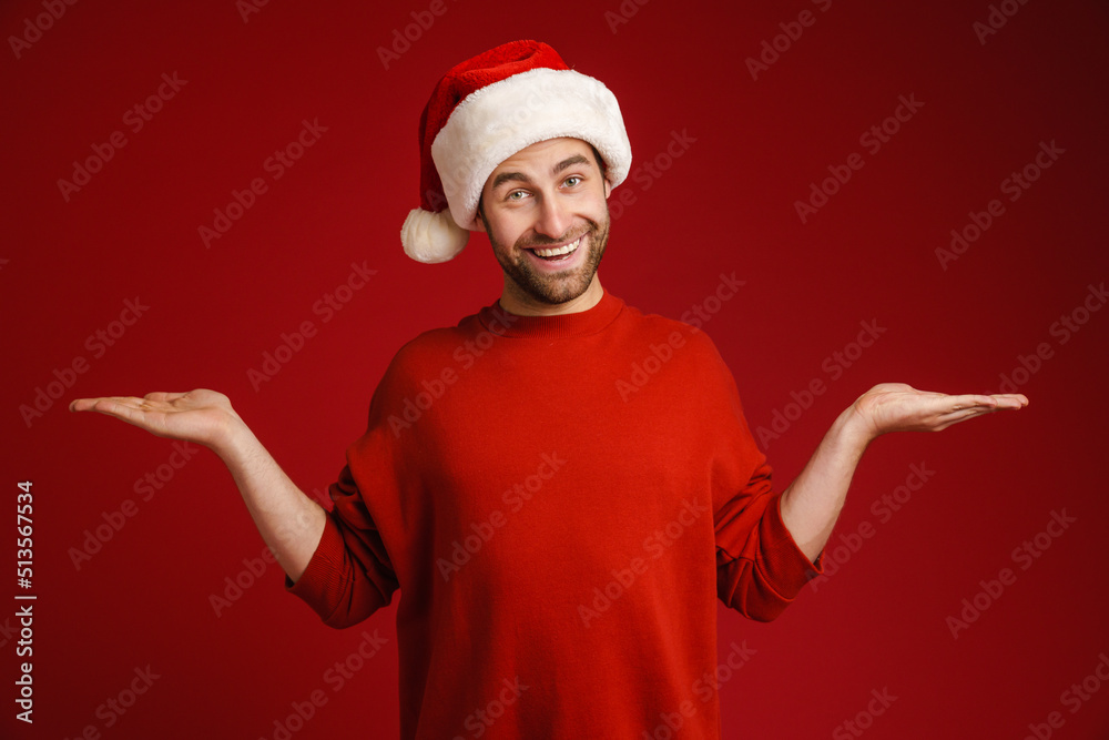 Young smiling man wearing santa hat holding copyspace Young smiling man wearing santa hat holding copyspace
