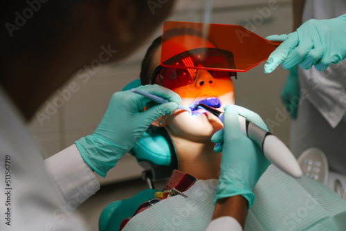 White girl sitting in medical chair while dentists fixing her teeth