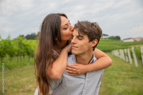 Young couple in the vineyard embraced as the girl in love kisses her love on the forehead