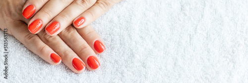 Close-up beautiful female hands with red nails on white towel background. Concept hand care  anti-wrinkles  anti-aging cream and spa salon. Soft skin  skincare concept.