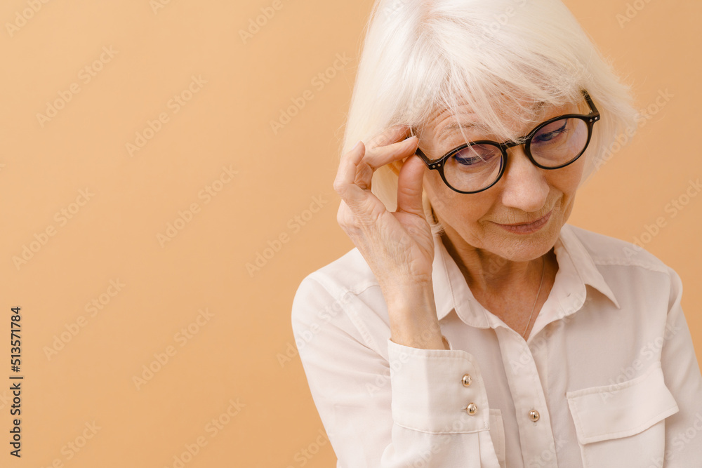 Beautiful senior woman in white shirt adjusting her glasses Beautiful senior woman in white shirt adjusting her glasses