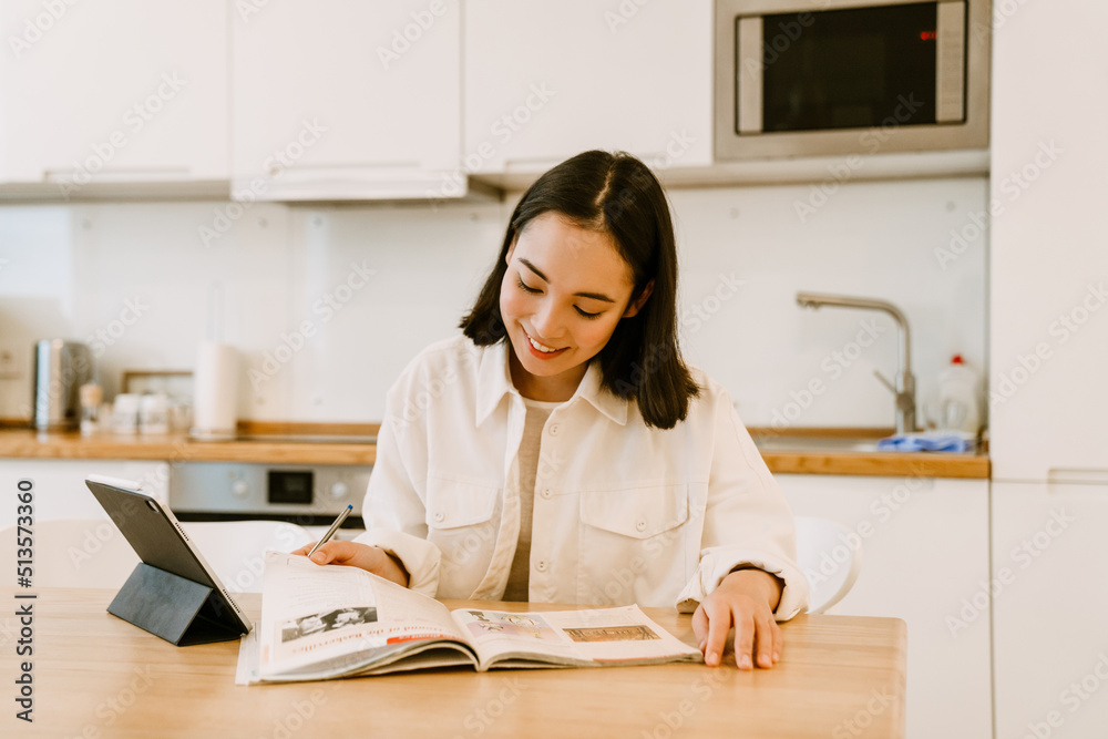 Young cute smiling asian woman with tablet studying at home Young cute smiling asian woman with tablet studying at home
