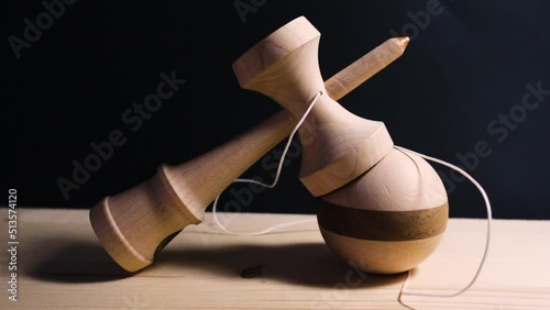 Tilt up on full shot of wooden kendama ken big cup on striped ball with string hanging off the side 
