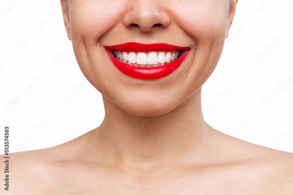 Obraz premium Cropped shot of young caucasian smiling woman with the even teeth isolated on a white background. Perfect smile with red lipstick. Teeth whitening. Oral hygiene, dental health care
