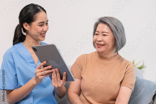 Asian nurse showing health checkup report to grandmother and giving advice. medical assisted living visit senior patient at home. Home nursing and healthcare caregiver concept photo