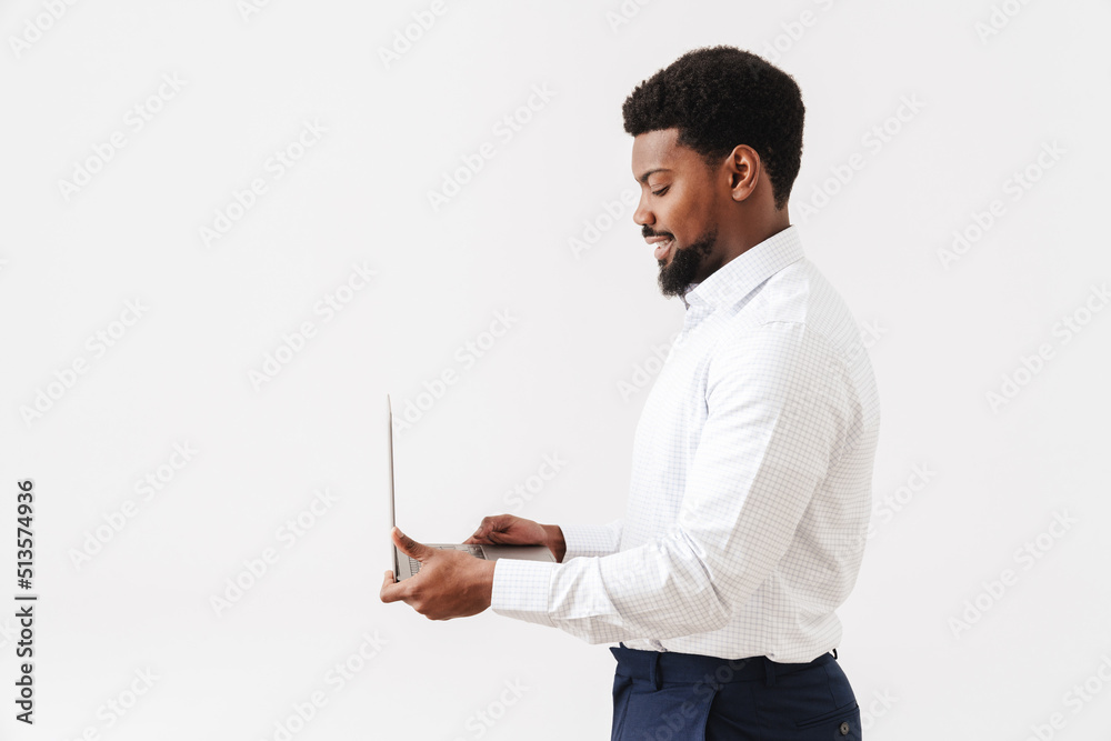 Black bearded man wearing shirt smiling and working with laptop Black bearded man wearing shirt smiling and working with laptop