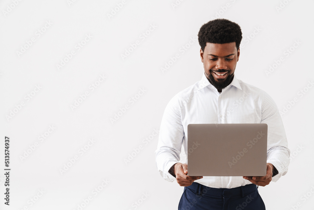 Black bearded man wearing shirt smiling and working with laptop Black bearded man wearing shirt smiling and working with laptop