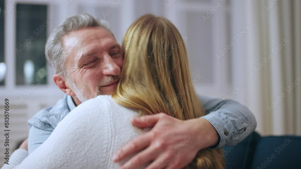 Middle-aged man and his daughter hugging on sofa, trust, family bonding Middle-aged man and his daughter hugging on sofa, trust, family bonding