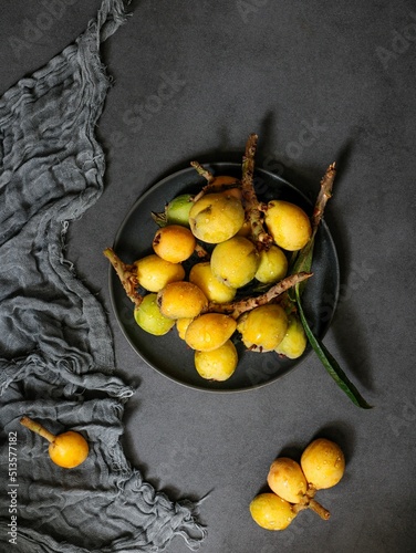 Top view shot of a plate of loquats on a grey fabric