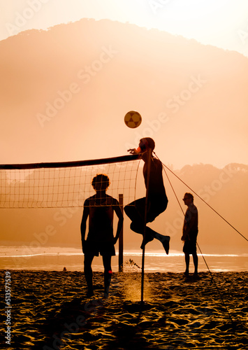 Silhouette of people playing footvolley on the Camburi beach, Brazil
