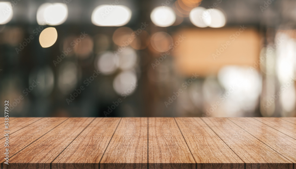 Empty wooden table top with lights bokeh on blur restaurant background.