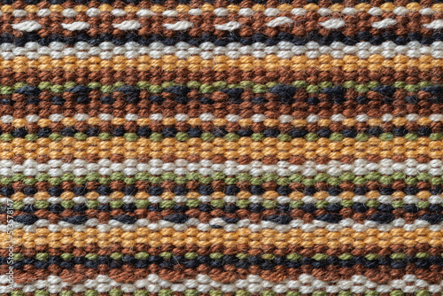 Plain weave fabric macro texture. Cloth background with horizontal strips of white, yellow, green, brown and black colors. Textile surface. Colorful woven fabric as design element. Weft and warp.