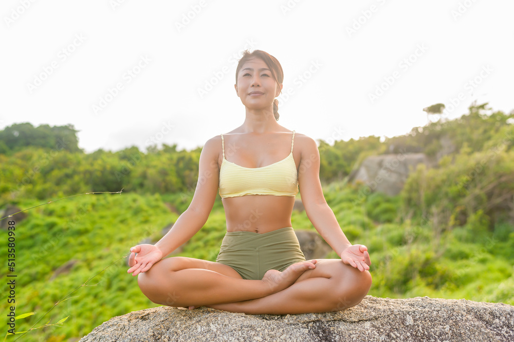 Beautiful asian woman in sportswear doing yoga on seaside mountain peak after trekking, Travel and meditation concept.