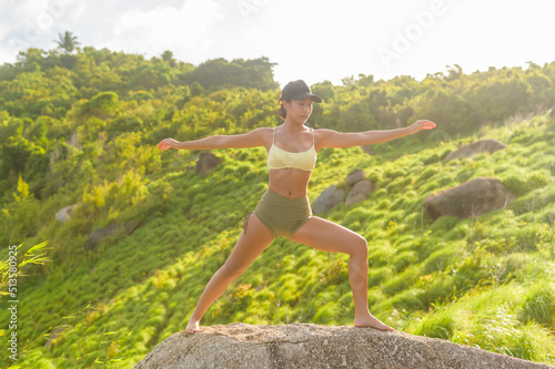 Beautiful asian woman in sportswear doing yoga on seaside mountain peak after trekking, Travel and meditation concept.