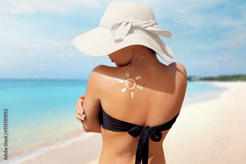 Girl Using Sunscreen to Skin. Beauty Woman Applying Sun Cream Creme on Tanned  Shoulder In Form Of The Sun.
