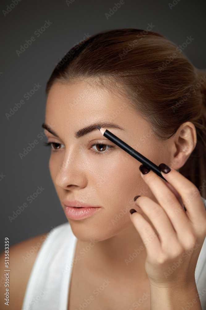 Eyebrows makeup. Beautiful woman with perfect make-up contouring brows with eyebrow pencil. Closeup of female model beauty face with smooth skin on grey background. Eyebrows makeup. Beautiful woman with perfect make-up contouring brows with eyebrow pencil. Closeup of female model beauty face with smooth skin on grey background.