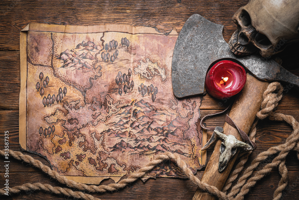 Map of ancient lands. Ancient journey concept. Old map and battle axe on the wooden flat lay table background.