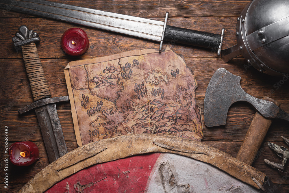 Map of ancient lands. Ancient journey concept. Old map and battle axe on the wooden flat lay table background. - obrazy, fototapety, plakaty 