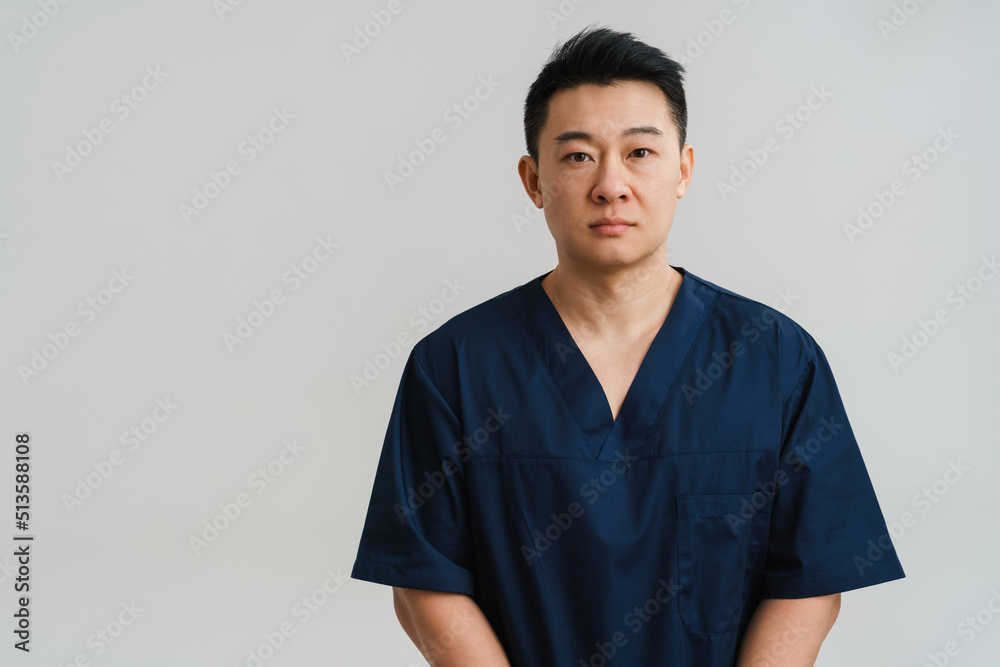 Adult asian man wearing medical uniform posing at camera Adult asian man wearing medical uniform posing at camera