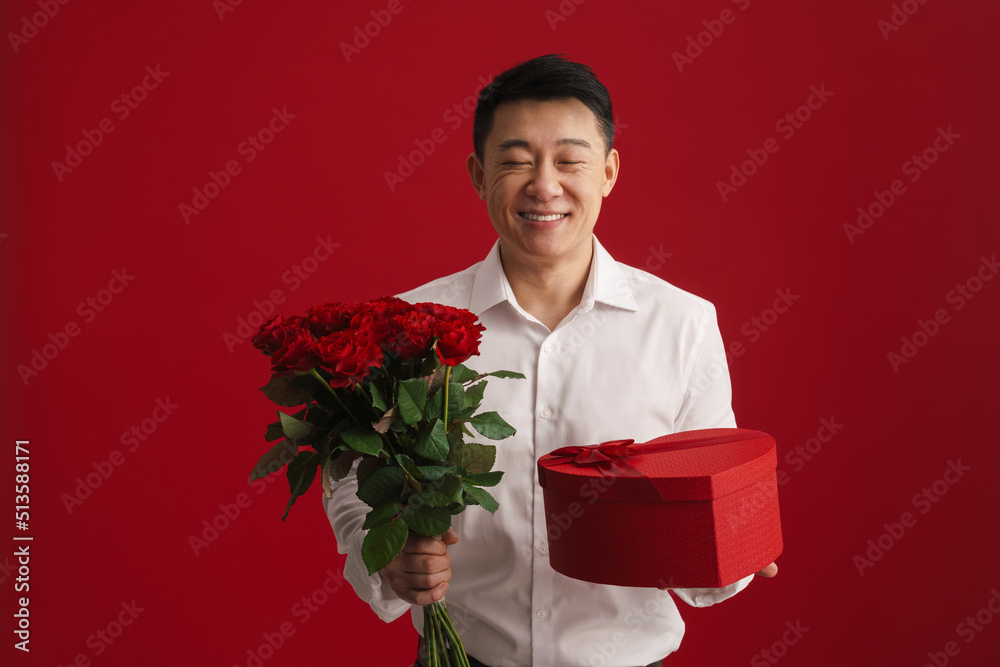 Adult asian man wearing white shirt holding rose bouquet and gift box Adult asian man wearing white shirt holding rose bouquet and gift box