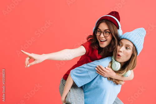 Принти на полотні Two young happy girls with headphones doing piggyback ride
