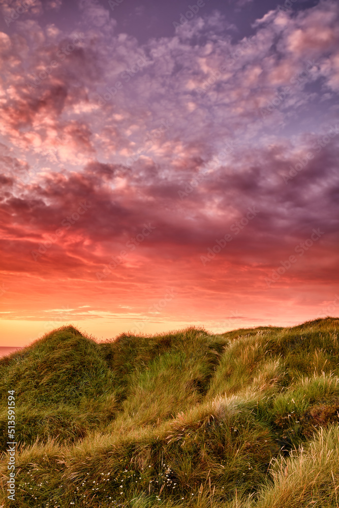 Copyspace landscape of sunset on coast of Jutland in Loekken, Denmark. Sun setting on empty beach at dusk over hills and meadows. Dramatic sunrise in morning with copy space. Pink sky on coastline