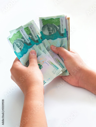 close-up of a woman's hands holding 100,000 Colombian peso banknotes on a white background