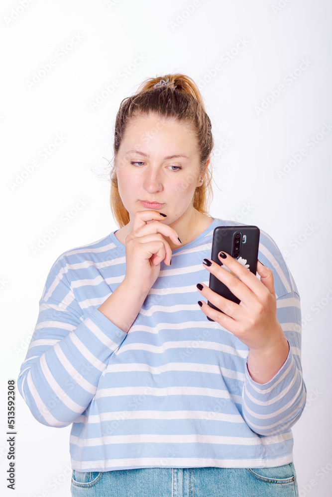 Young, beautiful woman looks thoughtfully at a smartphone Young, beautiful woman looks thoughtfully at a smartphone
