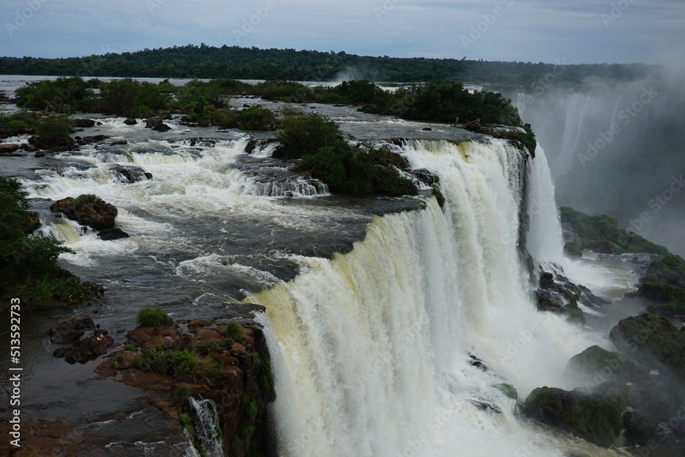 The photo shows a stunning view from the top of the Iguazu Falls — a complex of 275 waterfalls on the Iguazu River, located on the border of Brazil and Argentina. The photo shows a stunning view from the top of the Iguazu Falls — a complex of 275 waterfalls on the Iguazu River, located on the border of Brazil and Argentina.