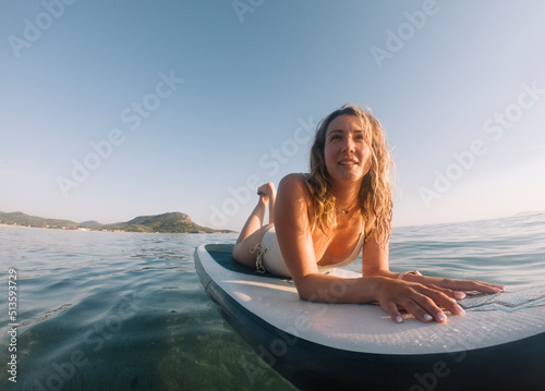 Low angle view of smiling woman lying down on paddle board