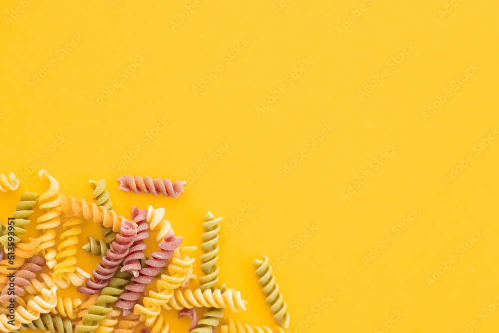 Beautiful Italian uncooked colored farfalle pasta close-up on yellow background. horizontal top view