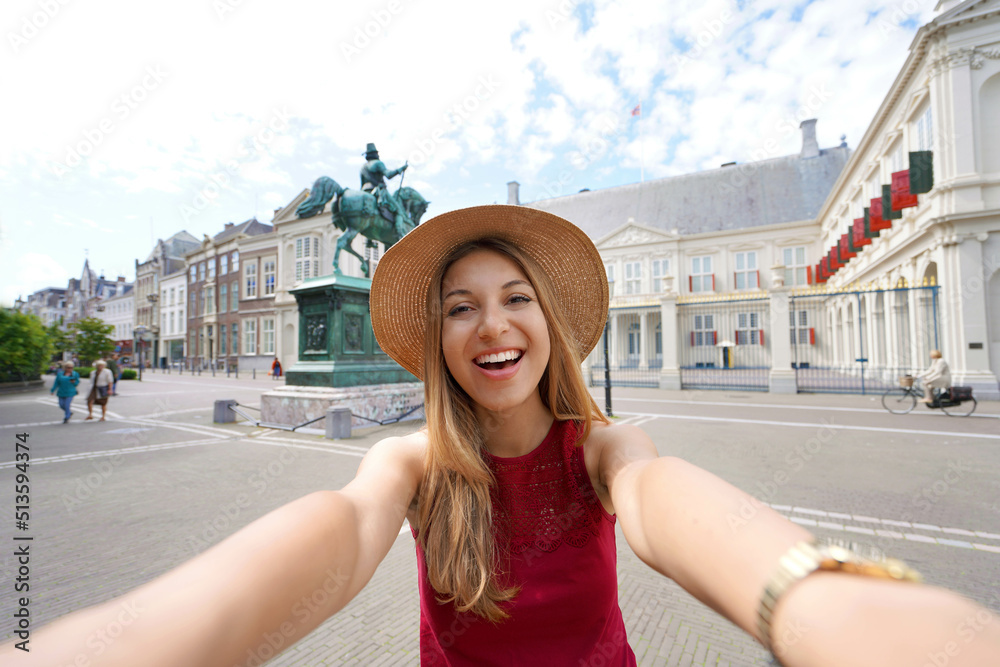 Happy tourist woman taking self portrait in front of Noordeinde Palace in The Hague, Netherlands