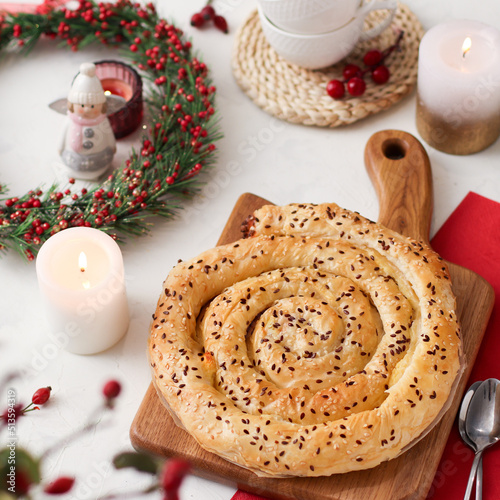 Homemade borek (burek) vertuta snail pie Spiral-shaped with cottage cheese close-up on the table with christmas decor photo