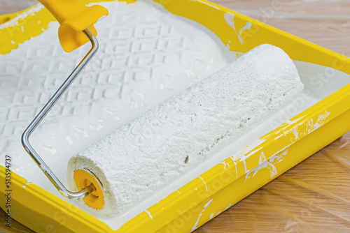 Paint roller in paint tray with white color. Repair and painting in the house. Construction and painting works.