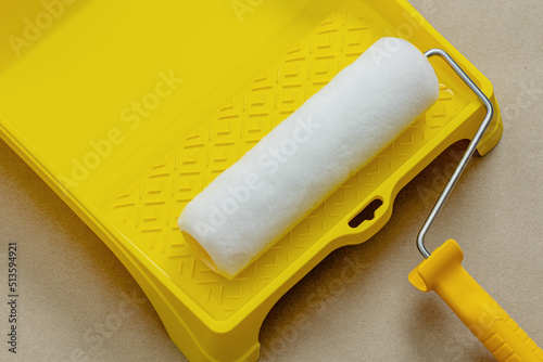 Paint roller in paint tray with white color. Repair and painting in the house. Construction and painting works.