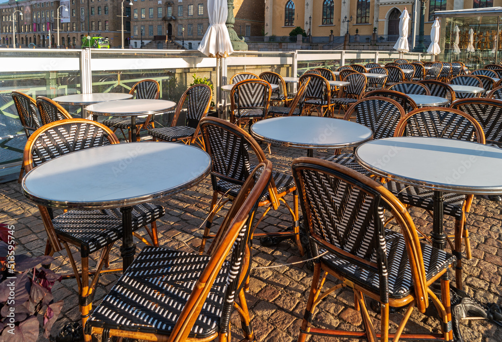 European outdoor cafe located on the bridge over the river. Cityscape with chairs and tables of a street restaurant in Sweden.