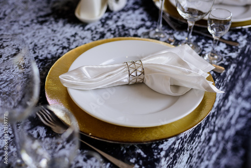 White plates, silver cutlery, glasses on the table with a velvet tablecloth. 