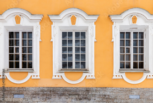 Three windows in white frames and decoration of yellow wall