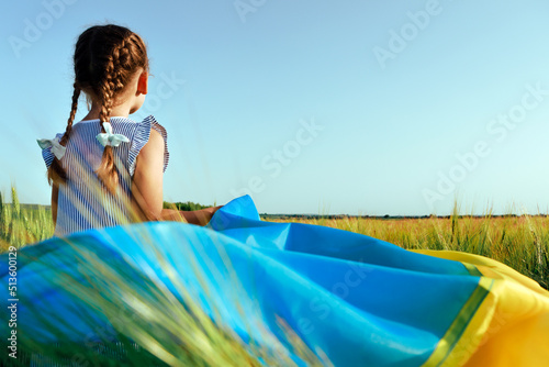 Little girl with Ukrainian flag in wheat field.Happy boy celebrating Independence Day. © Ruslan Ivantsov