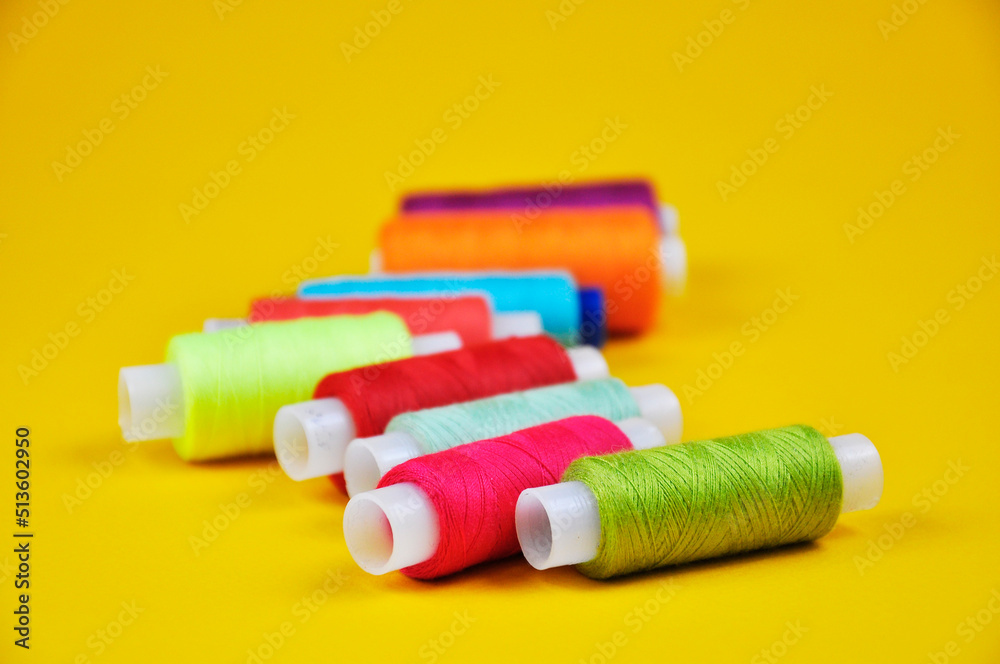 Reels with multicolored threads on a yellow background. Blur. Reels with multicolored threads on a yellow background. Blur.
