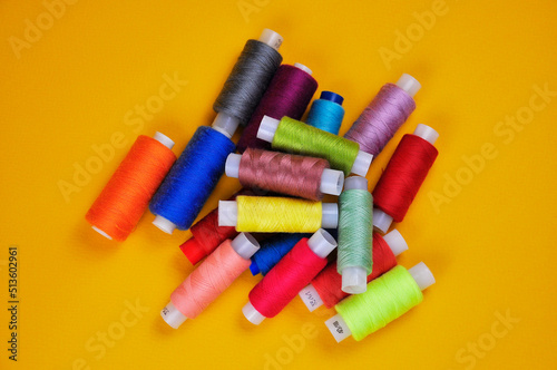 Spools with multicolored threads on a yellow background. Blurring background.
