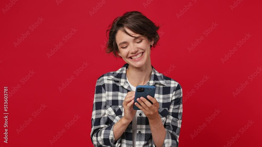 Dreamful cheery minded young woman 20s she wearing casual clothes hold using mobile cell phone typing browsing chatting send sms isolated on plain solid dark red color wall background studio portrait