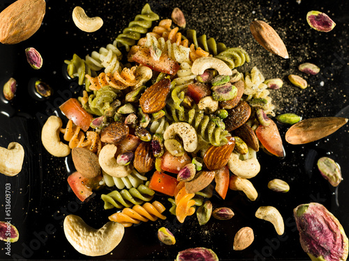 pasta salad, with nuts, tomato and condiments on black background