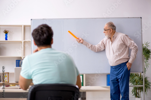 Old male teacher and young male student in the classroom photo