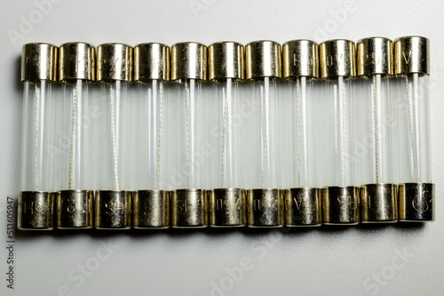 Small pile of clear electrical fuses on a white background. Set of glass fuses with filament inside. Macro picture. Current protection for electric circuits. photo