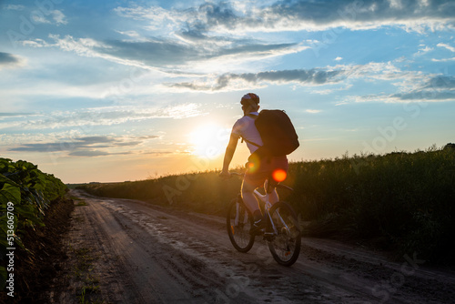 cyclist riding a bike at sunset in the field, active lifestyle. The concept of extreme cycling, free space. view from the back