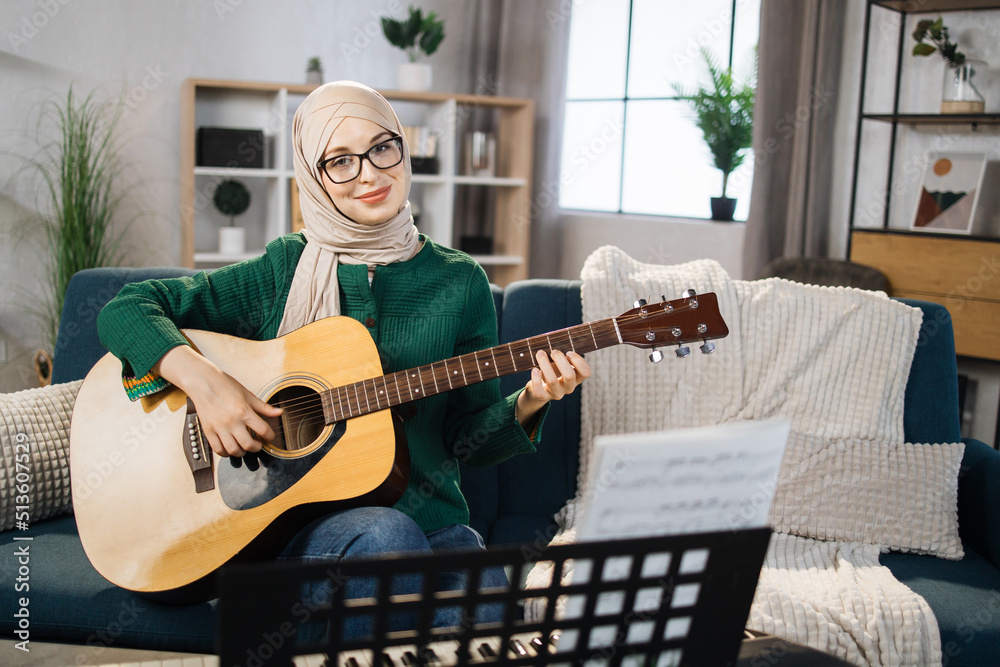 Portrait of young arab female with hijab playing on guitar. Pretty ...