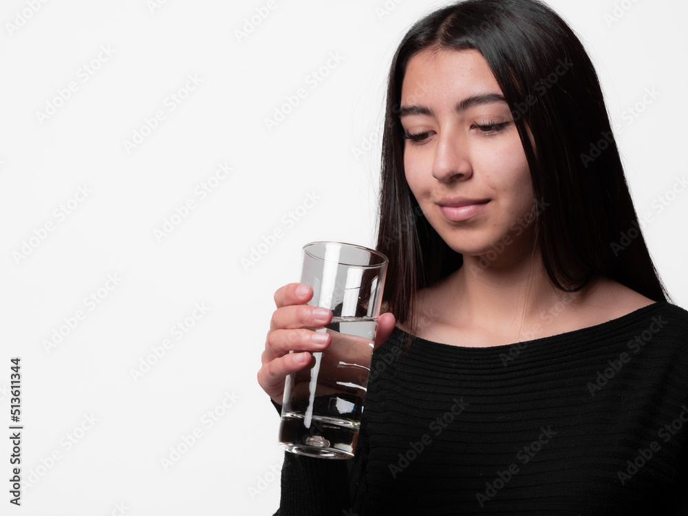 latina girl holding a glass of water, concept of hydration and the importance of water in good health. latina girl holding a glass of water, concept of hydration and the importance of water in good health.