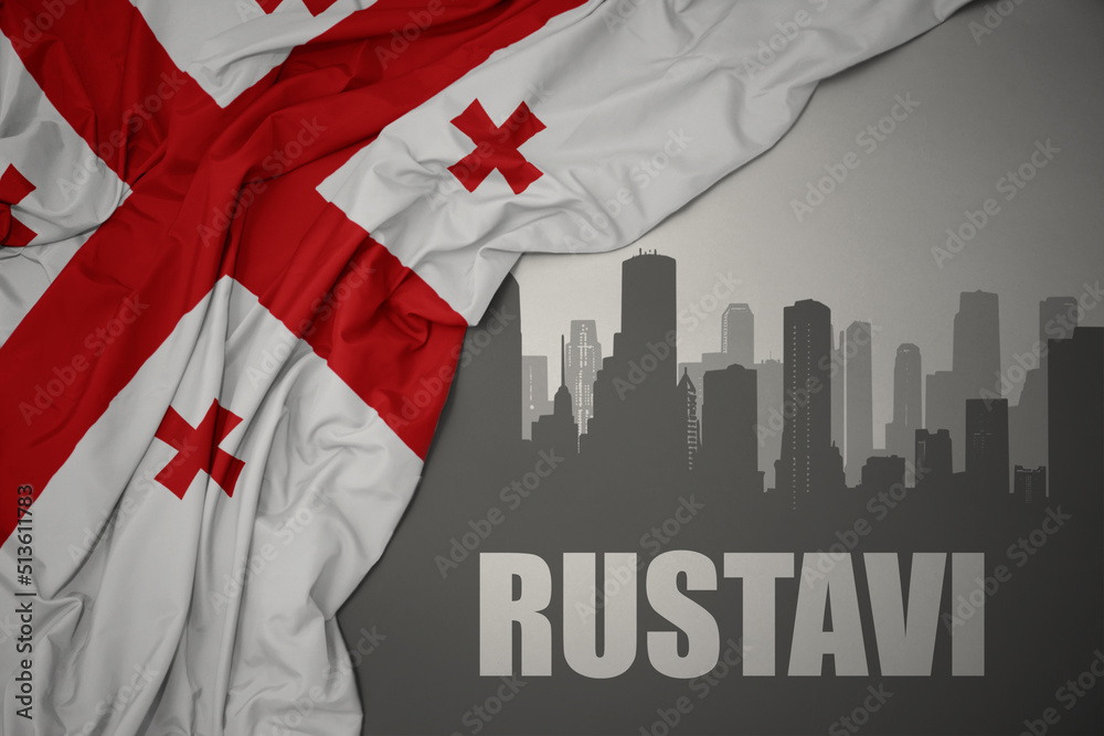 Fototapeta premium abstract silhouette of the city with text Rustavi near waving national flag of georgia on a gray background.