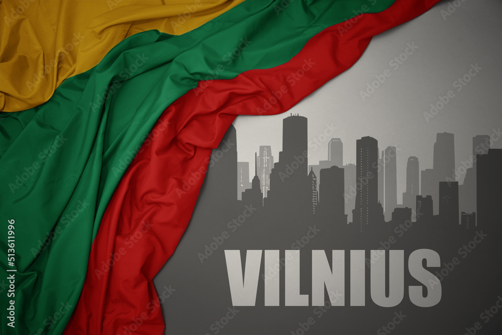 abstract silhouette of the city with text Vilnius near waving national flag of lithuania on a gray background.